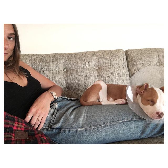 Lauren Deleo in a black sleeveless top and blue jeans with her pet  taking a nap on her lap.
